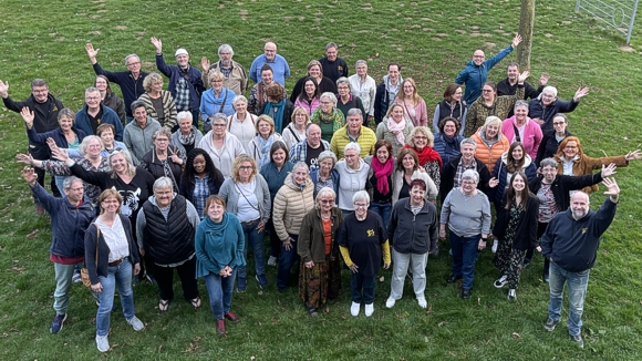 Bild: Chorfoto aufgenommen in einer Sporthalle im Rahmen eines Workshops. Die 
							Chromitglieder l�cheln und winken mit hochgehobenen H�nden.